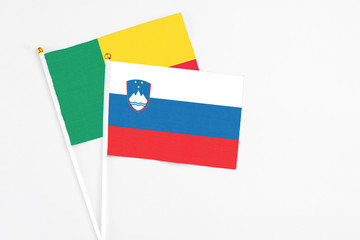 Slovenia and Benin stick flags on white background. High quality fabric, miniature national flag. Peaceful global concept.White floor for copy space.