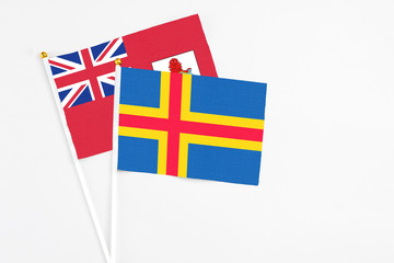 Aland Islands and Bermuda stick flags on white background. High quality fabric, miniature national...