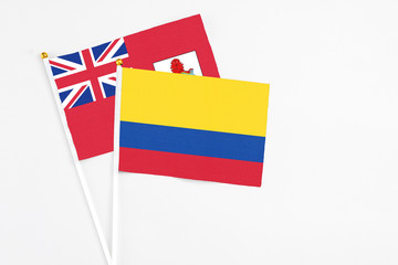 Colombia and Bermuda stick flags on white background. High quality fabric, miniature national flag. Peaceful global concept.White floor for copy space.