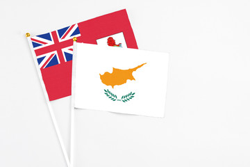Obraz premium Cyprus and Bermuda stick flags on white background. High quality fabric, miniature national flag. Peaceful global concept.White floor for copy space.