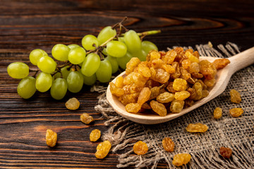 Raisin and green grape on dark wooden background.