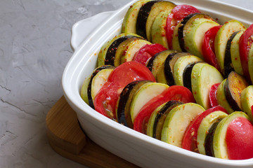 Ratatouille on a white plate. Recipes for the oven. Fast food. Cut vegetables. Tomato, zucchini,...