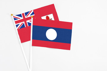 Laos and Bermuda stick flags on white background. High quality fabric, miniature national flag. Peaceful global concept.White floor for copy space.