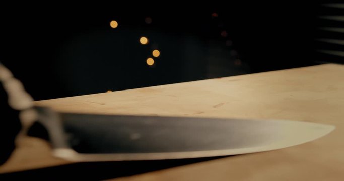 Person with black skeleton halloween gloves pulls a clean butcher-knife from a table. Cinematic slow motion, 4k