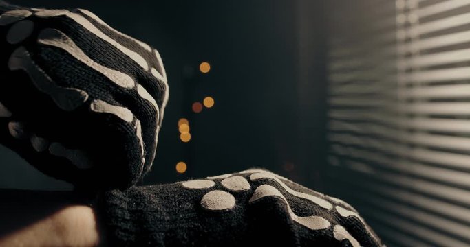 Person puts on black skeleton halloween gloves in a  low lit room. Cinematic slow-motion. 4k