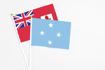 Micronesia and Bermuda stick flags on white background. High quality fabric, miniature national flag. Peaceful global concept.White floor for copy space.