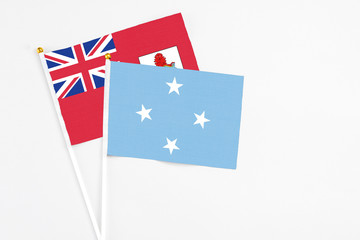 Fototapeta premium Micronesia and Bermuda stick flags on white background. High quality fabric, miniature national flag. Peaceful global concept.White floor for copy space.