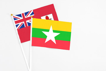 Fototapeta premium Myanmar and Bermuda stick flags on white background. High quality fabric, miniature national flag. Peaceful global concept.White floor for copy space.