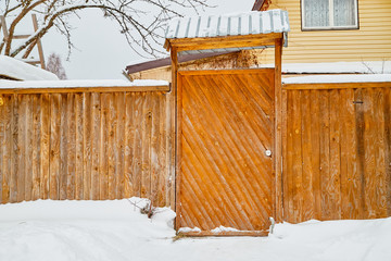 Wooden gate in traditional Russian style and snow around in winter