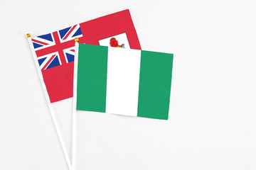 Nigeria and Bermuda stick flags on white background. High quality fabric, miniature national flag. Peaceful global concept.White floor for copy space.