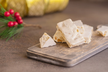 Turron, typical Christmas sweet in Spain. Almond nougat on dark wooden background with Christmas decoration