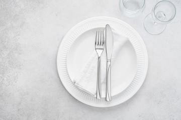 Restaurant table setting with white plates, glasses and cutlery.