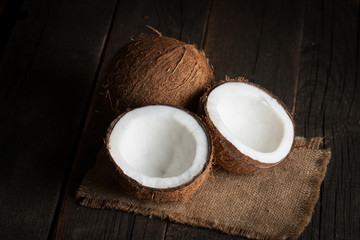Ripe half cut coconut on a wooden background. Coconut cream and oil.