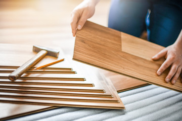 Man installing laminated wooden floors, Professional floor work measuring in new house.