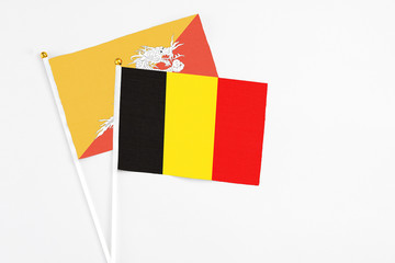 Belgium and Bhutan stick flags on white background. High quality fabric, miniature national flag. Peaceful global concept.White floor for copy space.