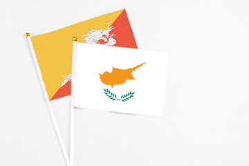 Obraz premium Cyprus and Bhutan stick flags on white background. High quality fabric, miniature national flag. Peaceful global concept.White floor for copy space.