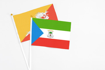 Equatorial Guinea and Bhutan stick flags on white background. High quality fabric, miniature national flag. Peaceful global concept.White floor for copy space.