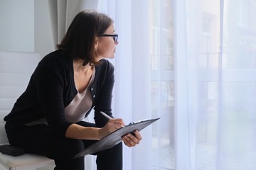 Mature business woman with clipboard looking out the window