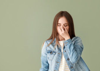 Young woman suffering from headache on color background