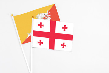 Georgia and Bhutan stick flags on white background. High quality fabric, miniature national flag. Peaceful global concept.White floor for copy space.