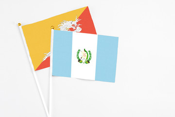 Guatemala and Bhutan stick flags on white background. High quality fabric, miniature national flag. Peaceful global concept.White floor for copy space.