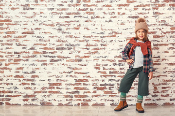 Obraz na płótnie Canvas Fashionable little girl in autumn clothes near brick wall