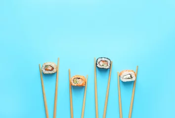 Fotobehang Smakelijke sushibroodjes en eetstokjes op kleurenachtergrond © Pixel-Shot