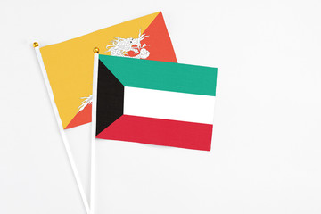 Kuwait and Bhutan stick flags on white background. High quality fabric, miniature national flag. Peaceful global concept.White floor for copy space.