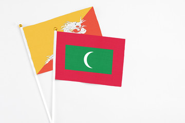 Maldives and Bhutan stick flags on white background. High quality fabric, miniature national flag. Peaceful global concept.White floor for copy space.