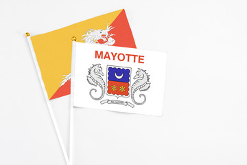 Mayotte and Bhutan stick flags on white background. High quality fabric, miniature national flag. Peaceful global concept.White floor for copy space.