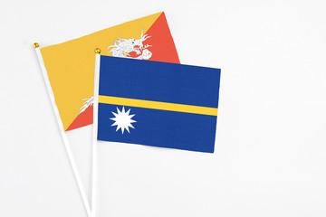 Nauru and Bhutan stick flags on white background. High quality fabric, miniature national flag. Peaceful global concept.White floor for copy space.