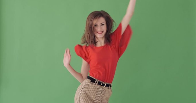 Excited young woman appearing dancing and disappearing over green background