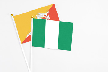 Nigeria and Bhutan stick flags on white background. High quality fabric, miniature national flag. Peaceful global concept.White floor for copy space.