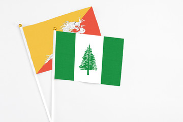 Norfolk Island and Bhutan stick flags on white background. High quality fabric, miniature national flag. Peaceful global concept.White floor for copy space.