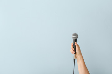 Female hand with microphone on color background