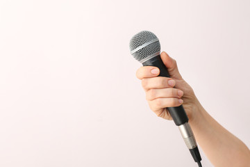 Female hand with microphone on light background