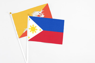 Philippines and Bhutan stick flags on white background. High quality fabric, miniature national flag. Peaceful global concept.White floor for copy space.