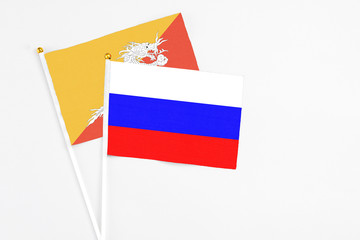 Russia and Bhutan stick flags on white background. High quality fabric, miniature national flag. Peaceful global concept.White floor for copy space.