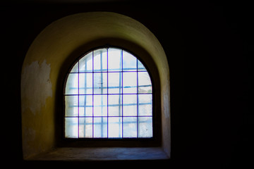 Castle prison window from darkness with stained glass and bars