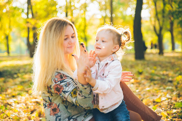 mather with little toddle daughter playing in autumn city public park