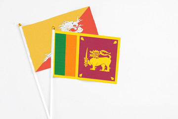 Sri Lanka and Bhutan stick flags on white background. High quality fabric, miniature national flag. Peaceful global concept.White floor for copy space.