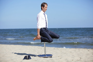 Caucasian business man exercising  on pneumatic stool  on the beach