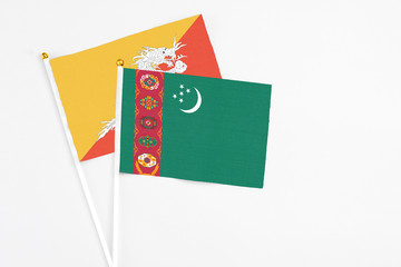 Turkmenistan and Bhutan stick flags on white background. High quality fabric, miniature national flag. Peaceful global concept.White floor for copy space.