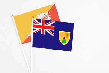 Turks And Caicos Islands and Bhutan stick flags on white background. High quality fabric, miniature national flag. Peaceful global concept.White floor for copy space.