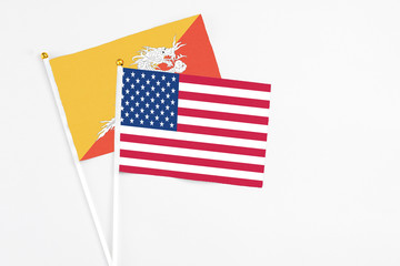 United States and Bhutan stick flags on white background. High quality fabric, miniature national flag. Peaceful global concept.White floor for copy space.