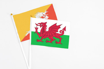 Obraz na płótnie Canvas Wales and Bhutan stick flags on white background. High quality fabric, miniature national flag. Peaceful global concept.White floor for copy space.