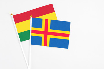 Aland Islands and Bolivia stick flags on white background. High quality fabric, miniature national flag. Peaceful global concept.White floor for copy space.