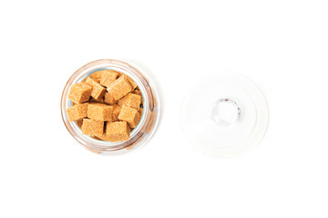 Sugar crystals and sugar cubes on a white table. Sugar cubes in a clear jar. Isolated background.
