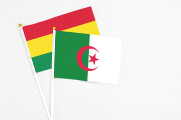 Algeria and Bolivia stick flags on white background. High quality fabric, miniature national flag. Peaceful global concept.White floor for copy space.