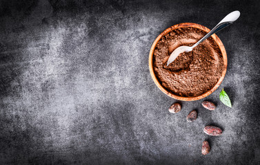 Cocoa beans and chocolate cacao powder with mint on top view. Copy space for text, dark stone table.